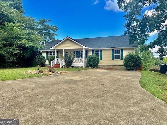 ranch-style house featuring covered porch and a front lawn