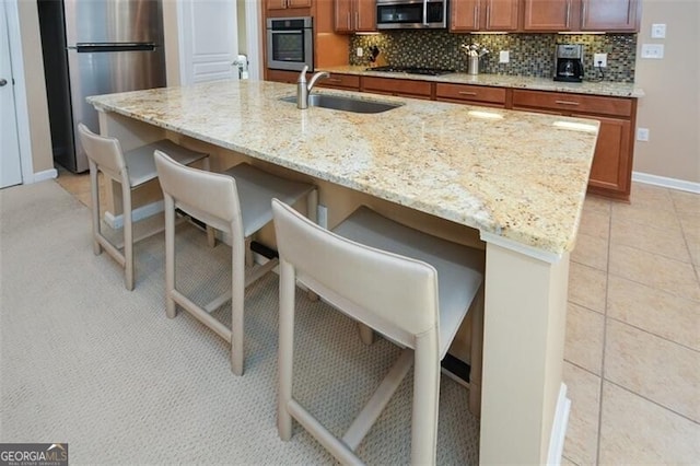 kitchen featuring a kitchen bar, backsplash, sink, and appliances with stainless steel finishes