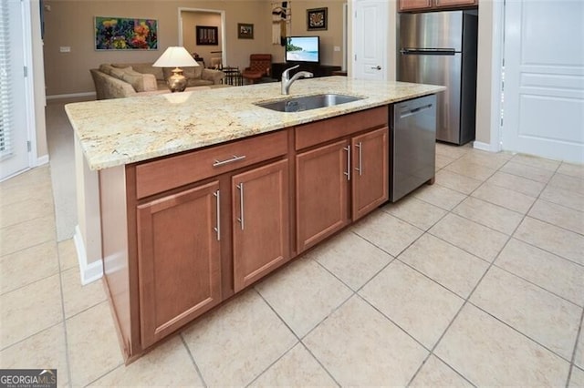 kitchen with a center island with sink, sink, light tile patterned floors, and stainless steel appliances