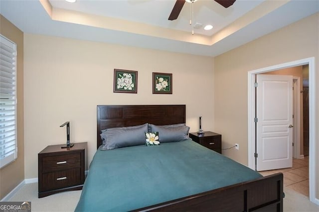 bedroom featuring a tray ceiling, ceiling fan, and light carpet