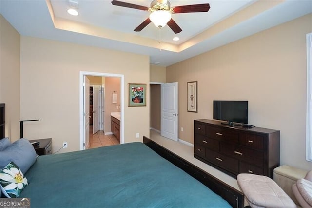 tiled bedroom with ceiling fan, ensuite bathroom, and a tray ceiling