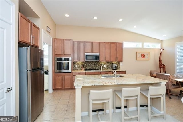 kitchen with sink, stainless steel appliances, an island with sink, a breakfast bar, and light tile patterned floors