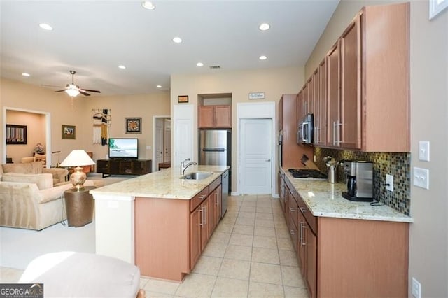 kitchen featuring light stone countertops, appliances with stainless steel finishes, ceiling fan, sink, and an island with sink