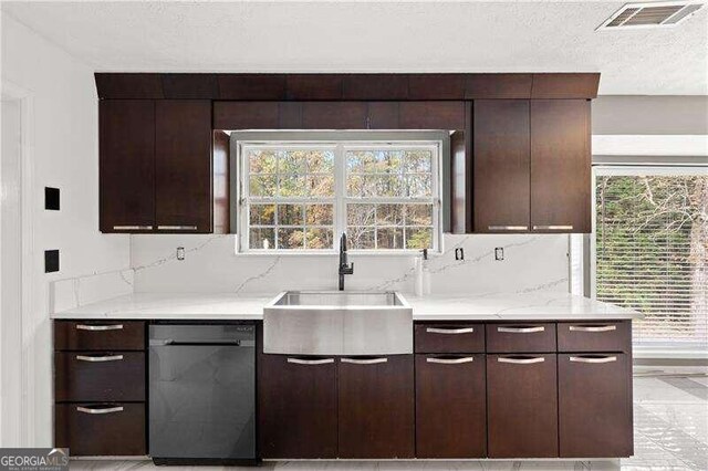 kitchen featuring stainless steel dishwasher, dark brown cabinetry, light stone countertops, and sink