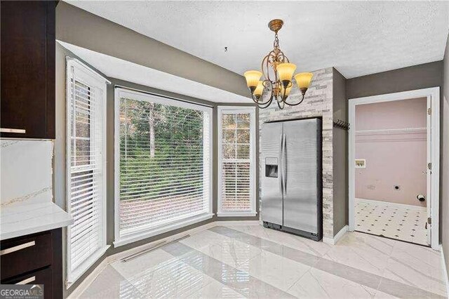 unfurnished dining area with a textured ceiling and an inviting chandelier