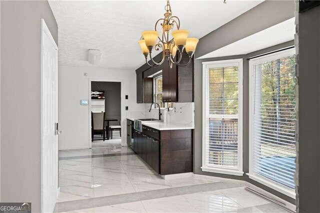 kitchen featuring dark brown cabinetry, sink, a chandelier, and a textured ceiling