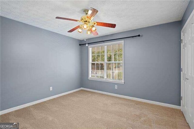 carpeted spare room with ceiling fan and a textured ceiling