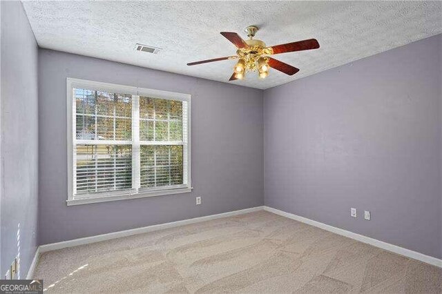 carpeted empty room featuring ceiling fan and a textured ceiling