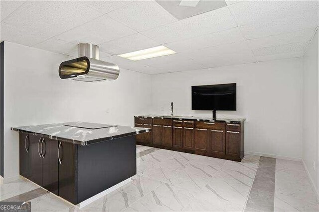 kitchen featuring kitchen peninsula, dark brown cabinets, a drop ceiling, and range hood