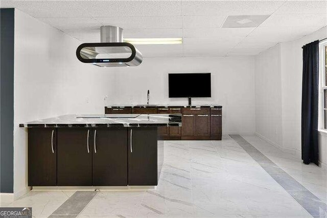 bar featuring dark brown cabinets and a drop ceiling