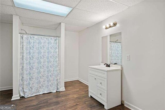 bathroom with hardwood / wood-style floors, vanity, and a drop ceiling