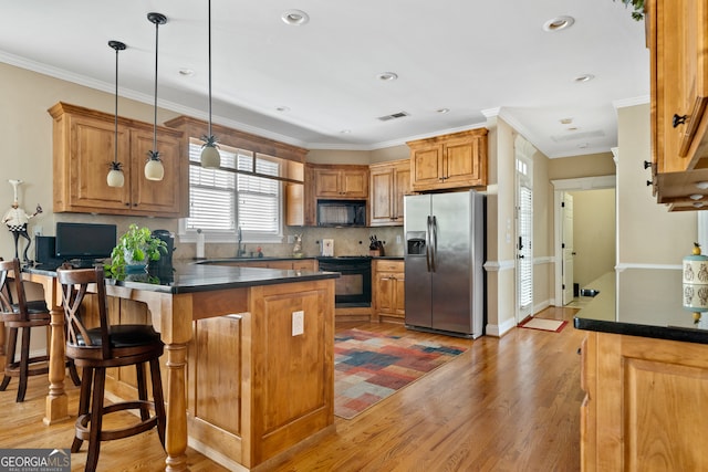 kitchen featuring crown molding, hanging light fixtures, black appliances, and light hardwood / wood-style flooring