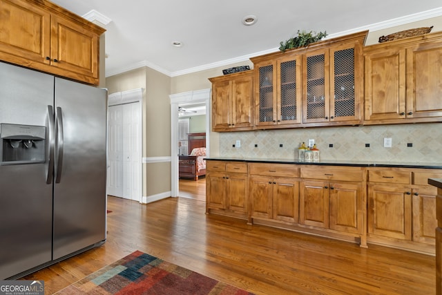 kitchen featuring wood-type flooring, stainless steel fridge with ice dispenser, backsplash, and ornamental molding