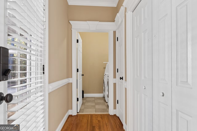 hall with independent washer and dryer, crown molding, and hardwood / wood-style flooring