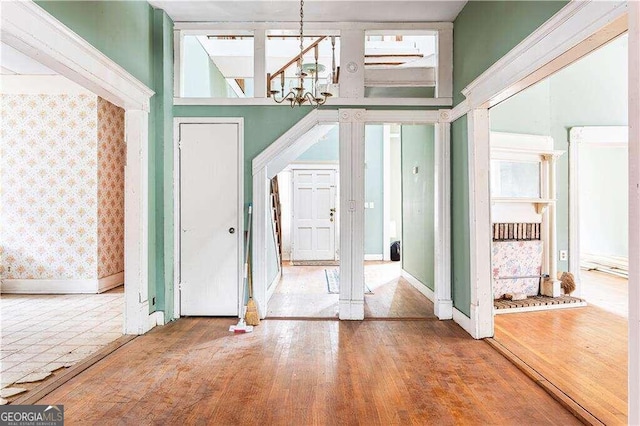 foyer entrance featuring hardwood / wood-style floors, a towering ceiling, and a notable chandelier