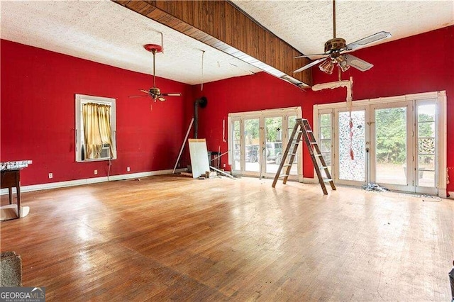 unfurnished living room featuring ceiling fan, french doors, hardwood / wood-style floors, and a textured ceiling