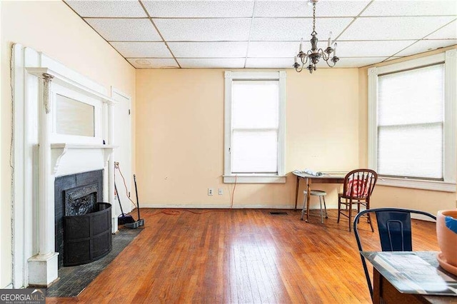 sitting room with a chandelier, a paneled ceiling, hardwood / wood-style flooring, and a fireplace