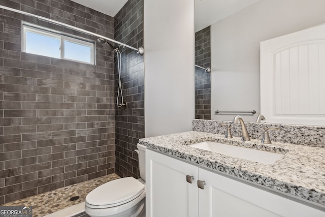 bathroom with vanity, toilet, and a tile shower