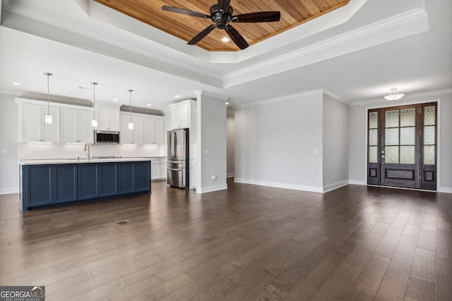 kitchen with blue cabinetry, white cabinetry, dark wood-type flooring, pendant lighting, and a tray ceiling