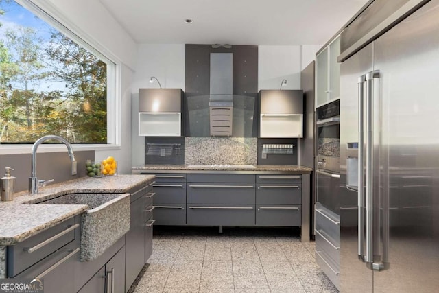 kitchen with tasteful backsplash, light stone counters, gray cabinetry, sink, and black appliances