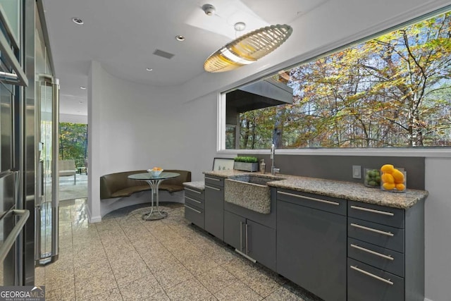 kitchen featuring light stone counters and sink