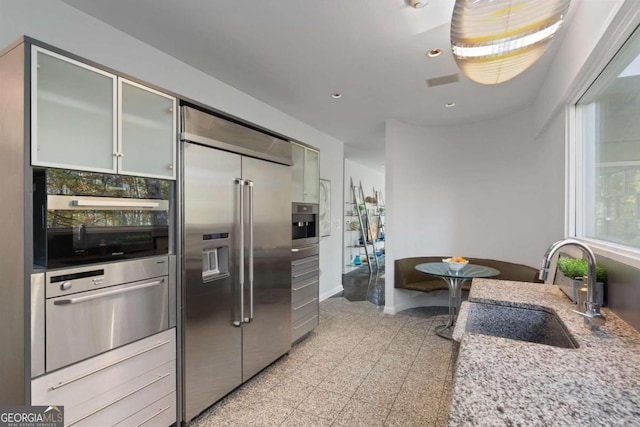 kitchen with light stone counters, sink, and appliances with stainless steel finishes