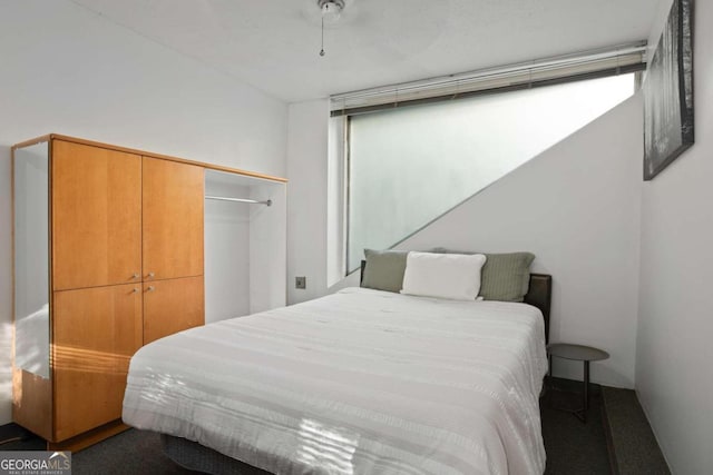 bedroom featuring dark colored carpet, multiple windows, and a closet