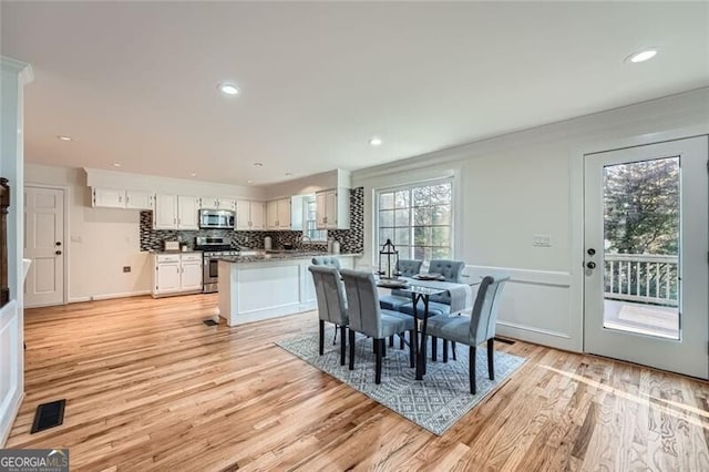 dining room with crown molding, plenty of natural light, and light wood-type flooring