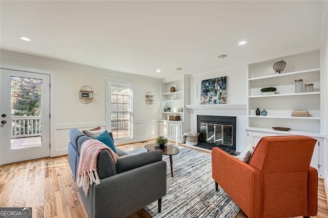 living room featuring built in shelves and light hardwood / wood-style floors