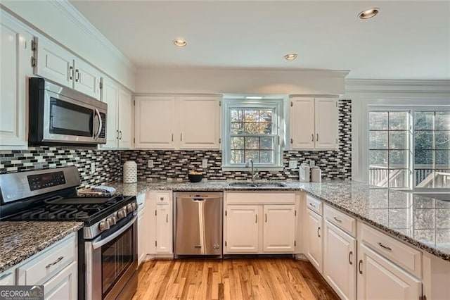 kitchen featuring a wealth of natural light, white cabinets, stainless steel appliances, and light stone counters