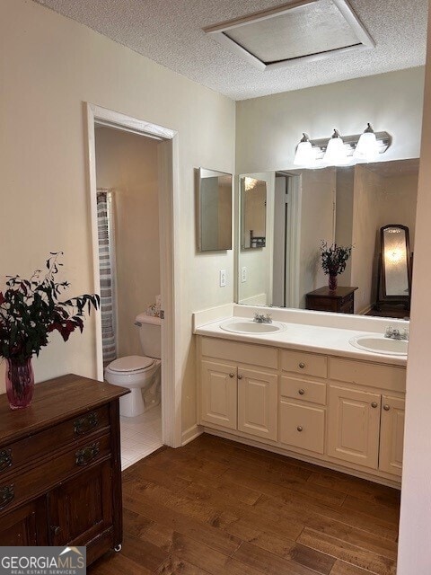 bathroom with hardwood / wood-style floors, vanity, a textured ceiling, and toilet