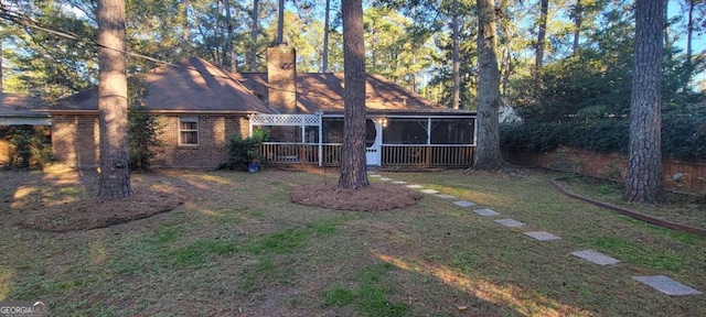 back of house with a lawn and a sunroom