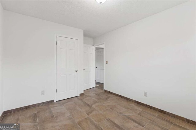 6166 Laurel Wood Trl, Flowery Branch, GA 30542 - unfurnished bedroom with baseboards and a textured ceiling