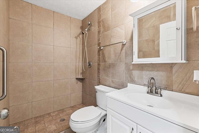 bathroom featuring vanity, a textured ceiling, toilet, and tile walls