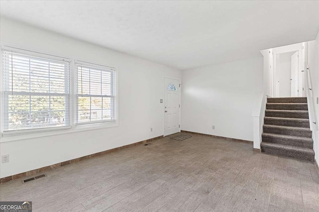 6166 Laurel Wood Trl, Flowery Branch, GA 30542 - unfurnished living room featuring baseboards, stairway, and light wood-style floors
