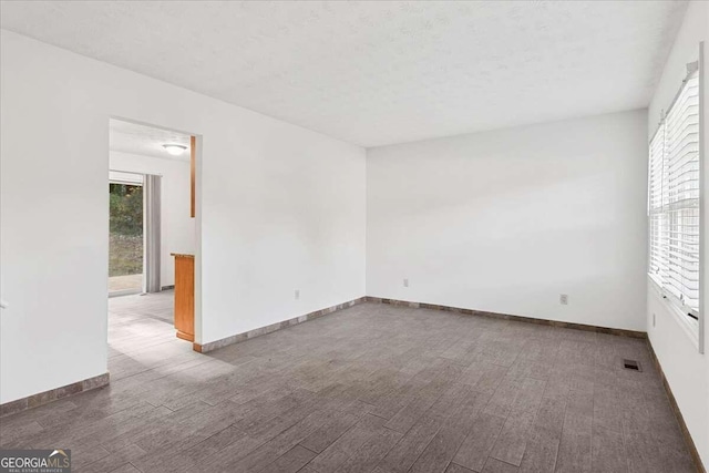 unfurnished room with hardwood / wood-style floors and a textured ceiling