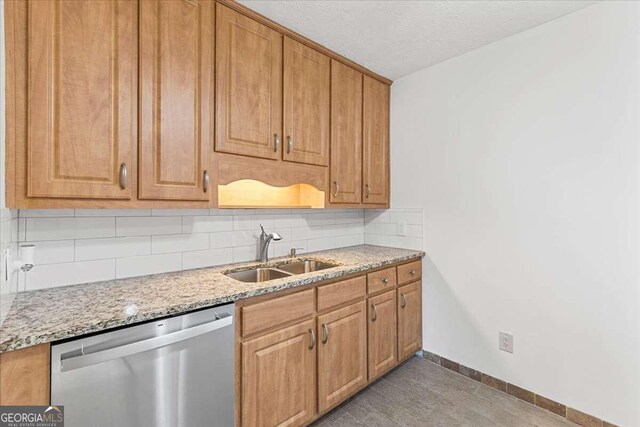 kitchen with tasteful backsplash, light stone counters, a textured ceiling, sink, and dishwasher