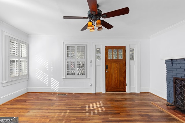 entryway with a fireplace, hardwood / wood-style floors, ceiling fan, and ornamental molding