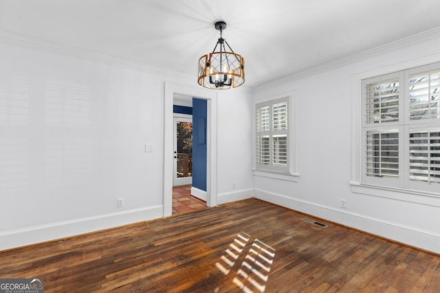 spare room featuring a notable chandelier, ornamental molding, and dark wood-type flooring