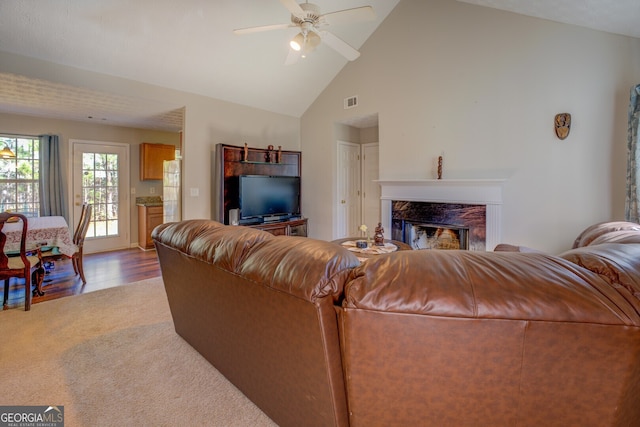 living room with ceiling fan, wood-type flooring, a fireplace, and high vaulted ceiling