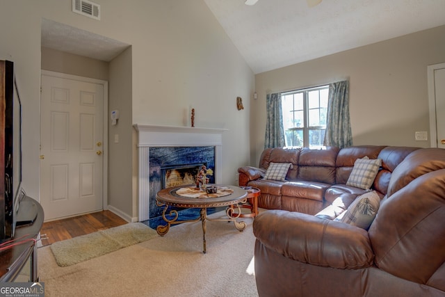 living room with a high end fireplace, lofted ceiling, and light wood-type flooring