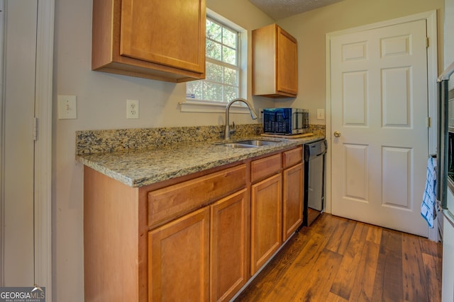 kitchen featuring dark hardwood / wood-style flooring, light stone counters, a textured ceiling, sink, and black dishwasher