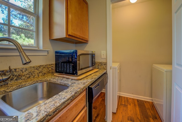 kitchen with dishwasher, dark wood-type flooring, sink, light stone counters, and washer / clothes dryer