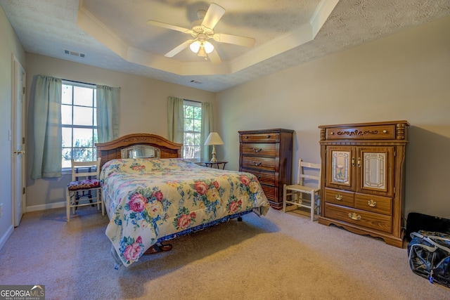 bedroom with carpet, ceiling fan, ornamental molding, and a tray ceiling