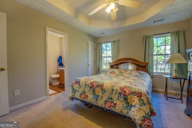 carpeted bedroom featuring ornamental molding, a textured ceiling, a tray ceiling, ceiling fan, and connected bathroom