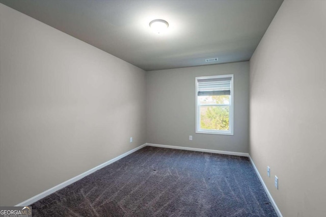 spare room featuring dark colored carpet