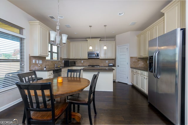 kitchen with hanging light fixtures, tasteful backsplash, dark hardwood / wood-style floors, a kitchen island, and appliances with stainless steel finishes