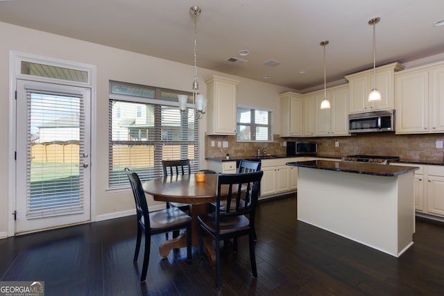 kitchen featuring white cabinetry, a center island, sink, dark hardwood / wood-style floors, and decorative light fixtures