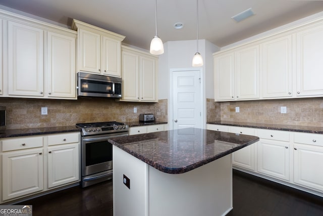 kitchen with decorative backsplash, a center island, stainless steel appliances, and dark stone counters