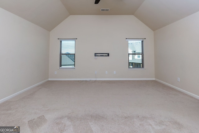 unfurnished room featuring light carpet, vaulted ceiling, ceiling fan, and a healthy amount of sunlight